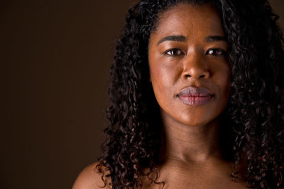 Portrait of young woman against black background