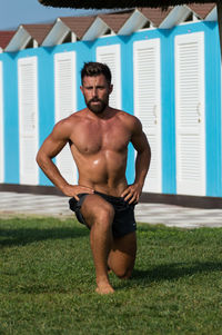 Shirtless man exercising on grass at park