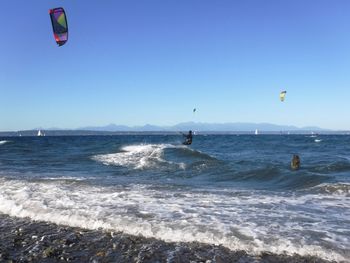 People in sea against clear sky