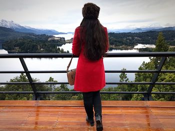 Rear view of woman standing on railing against mountain