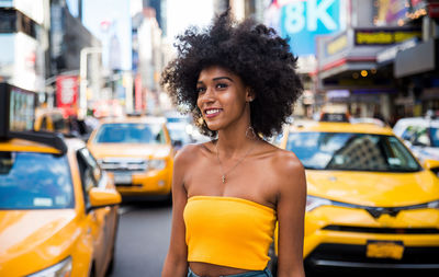 Thoughtful young woman with afro hairstyle standing on city street