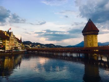 Bridge over river by buildings against sky