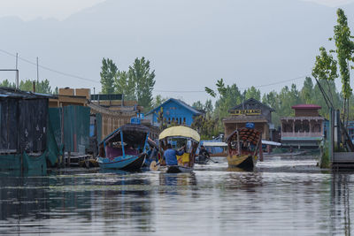 Fishing boats moored in river against sky