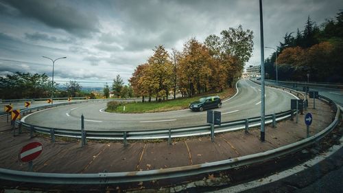 Empty road amidst trees against sky