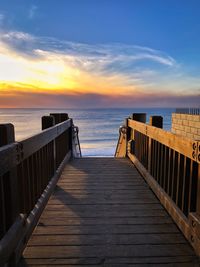 Pier over sea against sky during sunset