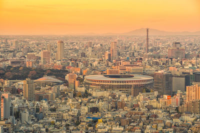 Aerial view of modern buildings in city against sky during sunset