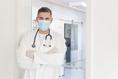Young confident physician or surgeon with medical mask standing in front of a surgery