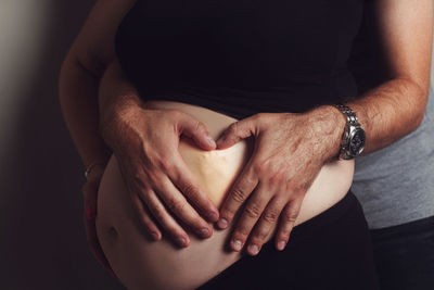 Midsection of woman touching heart shape