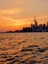 Scenic view of sea and buildings against sky during sunset