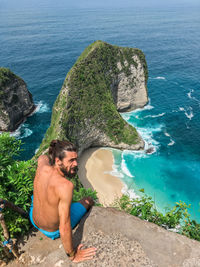 High angle view of shirtless man on rock at beach