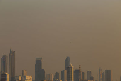 Modern buildings in city against sky during sunset