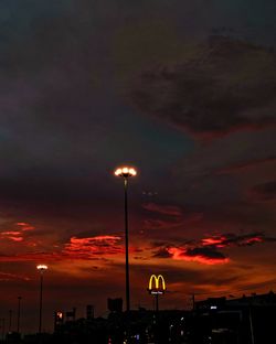 Illuminated street lights against sky at night