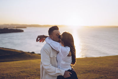 Young couple kissing on beach during sunset