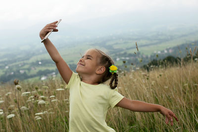 Side view of young woman with arms raised standing on field against sky