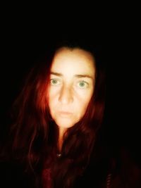 Close-up portrait of young woman against black background