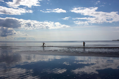 Silhouette people walking in calm sea