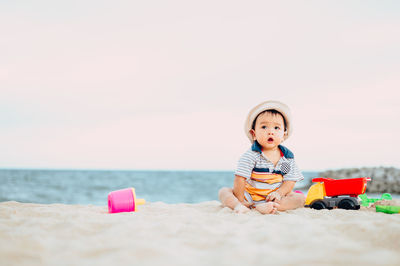 Boy toy on sand at beach against sky