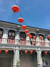 Low angle view of lanterns hanging by building