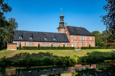 Temple by building against clear blue sky