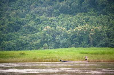 Man in boat on river by trees in forest