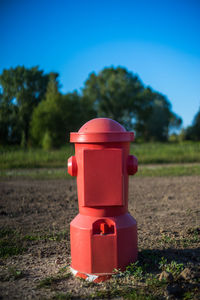 Red firehydrant on field against clear blue sky