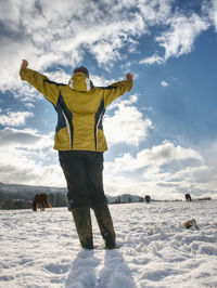 Woman farmer in yelow black work clothes and rubber boots gesture in snow. woman shout to horses