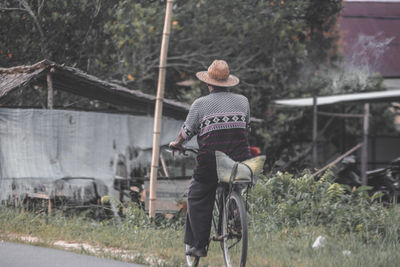 Rear view of man cycling on road