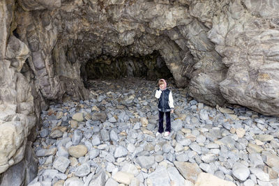 Portrait of smiling teenage girl standing against cave