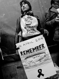 Woman holding poster while standing against wall