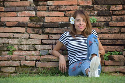 Portrait of woman leaning on brick wall