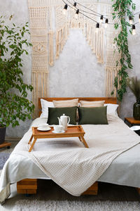 Cozy bedroom with macrame over bed and tea cup, apartment with light interior design 