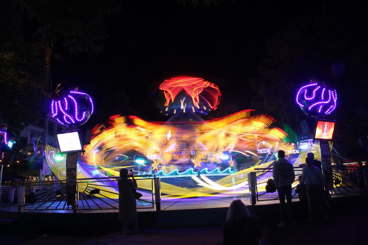 night, illuminated, arts culture and entertainment, light, motion, amusement park, multi colored, architecture, city, amusement park ride, sign, glowing, outdoors, long exposure, blurred motion, nature, communication, group of people, neon, leisure activity