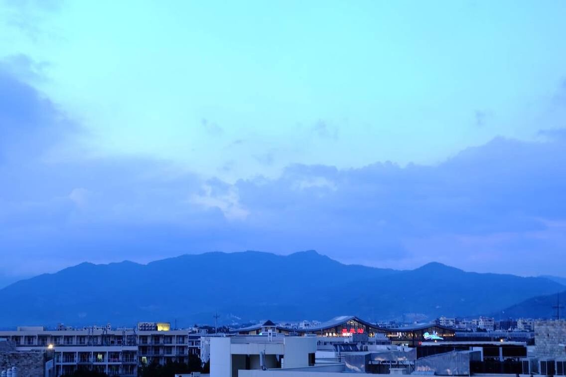 mountain, building exterior, architecture, built structure, mountain range, house, sky, residential structure, residential building, town, residential district, townscape, cloud - sky, scenics, city, roof, blue, cloud, nature, cityscape