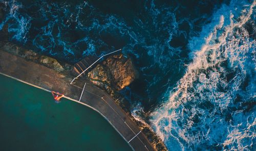 Aerial view of woman in infinity pool by sea