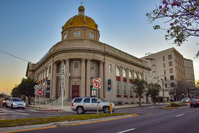 Cars on road by buildings against sky in city