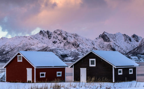 Houses against snowcapped mountains during sunset