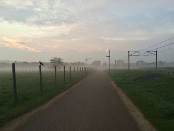 Road by landscape against sky during sunset