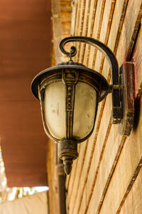 Low angle view of electric lamp hanging on wall