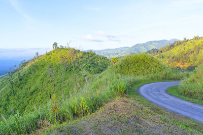 Scenic view of road by mountains against sky