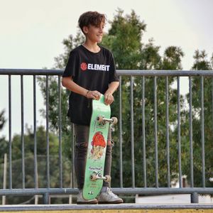 Young man standing on railing against trees