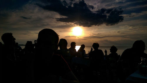 Silhouette people on beach against sky during sunset