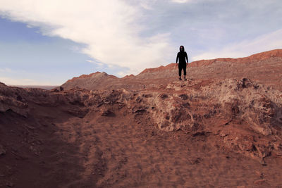 Man standing on rock on land against sky