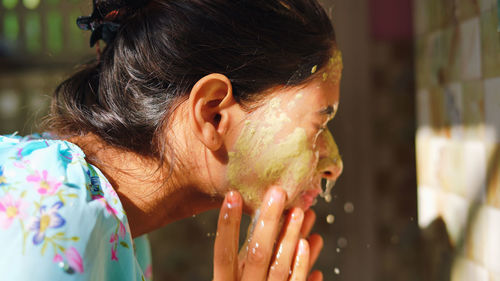 Beautiful woman is washing facial mask in bathroom after applying face mask.