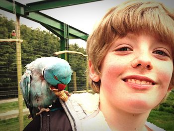 Close-up portrait of boy with parrot perching on shoulder