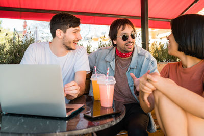 Friends sitting on mobile phone at restaurant