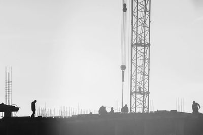 Silhouette people standing on construction site against clear sky
