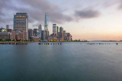 Scenic view of river and illuminated city against sky