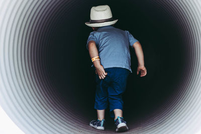 Rear view of boy standing against wall