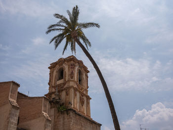 Low angle view of coconut palm tree by building against sky