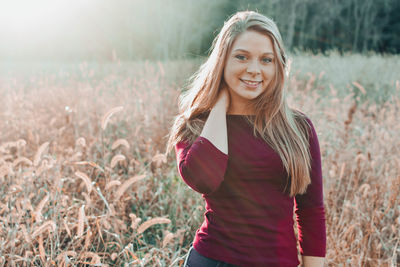 Portrait of smiling young woman standing on field